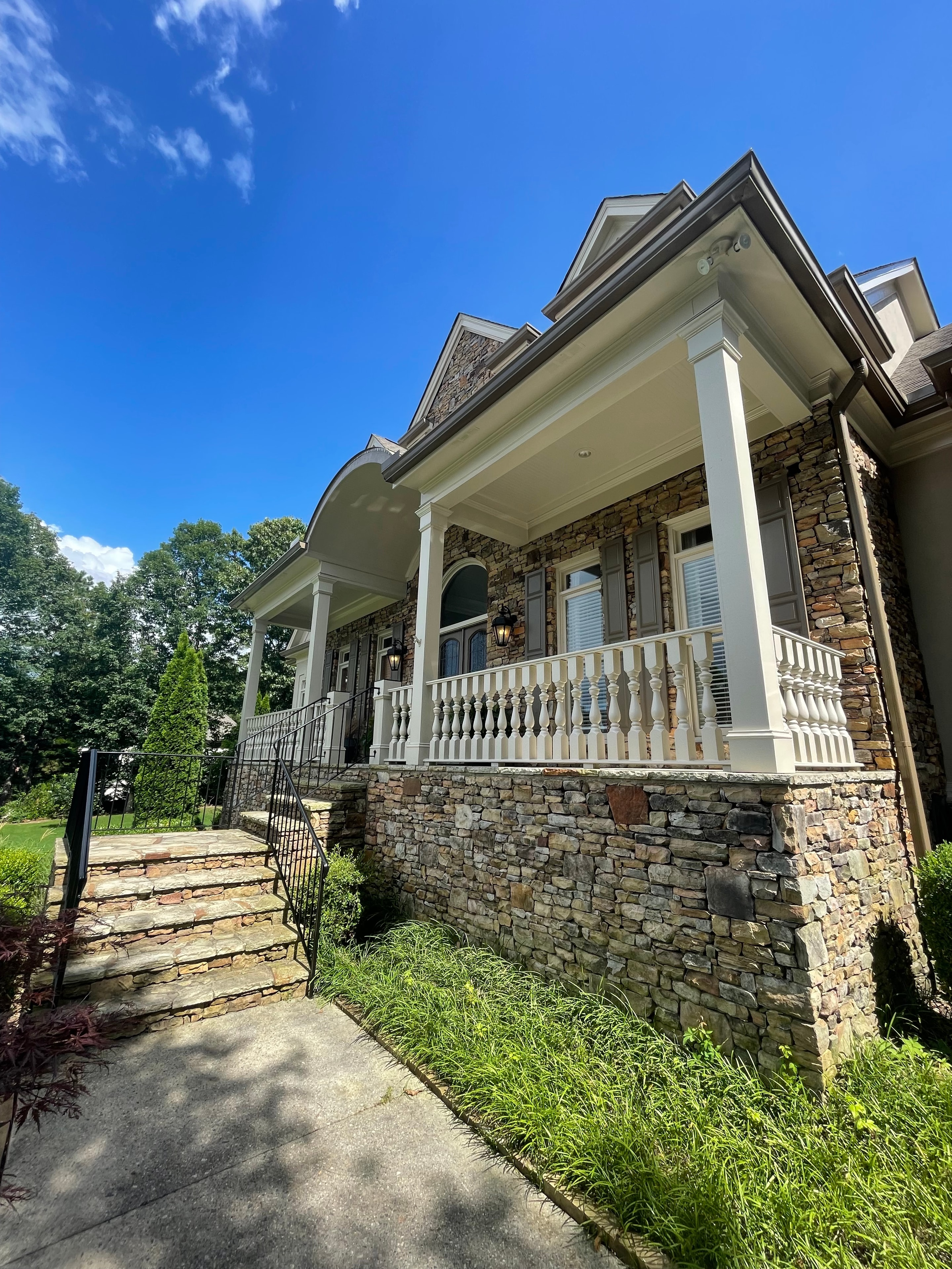 Estate home entry with white columns and stone wall exterior