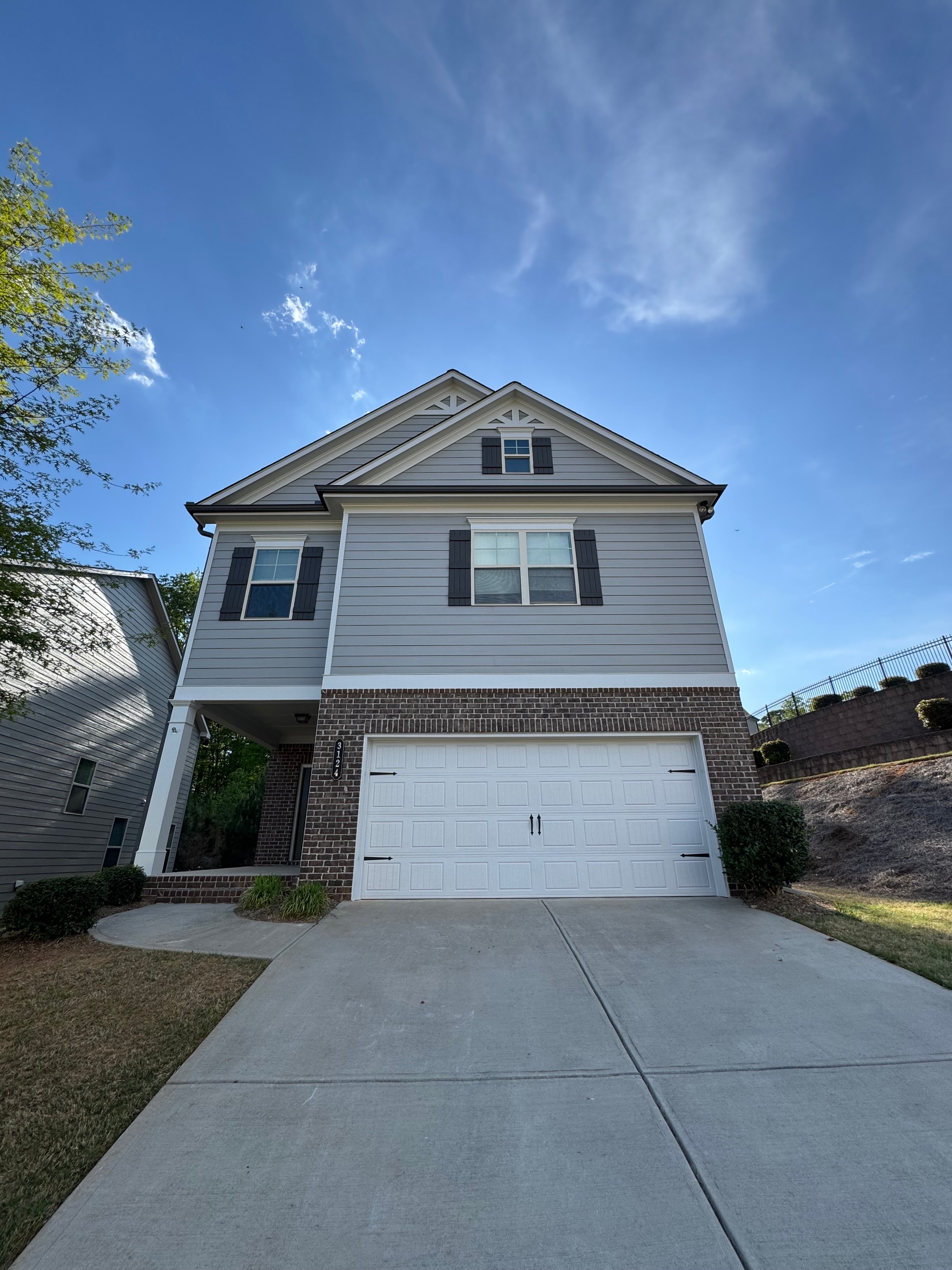 Home with gray board and batten siding and brick accents